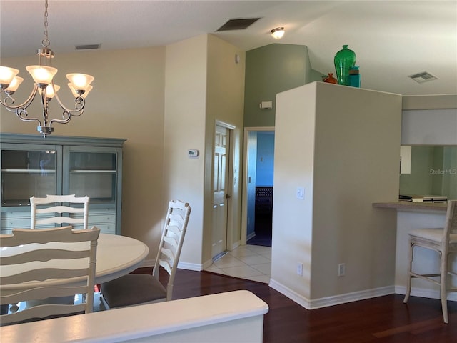 dining area featuring a notable chandelier, vaulted ceiling, and hardwood / wood-style flooring