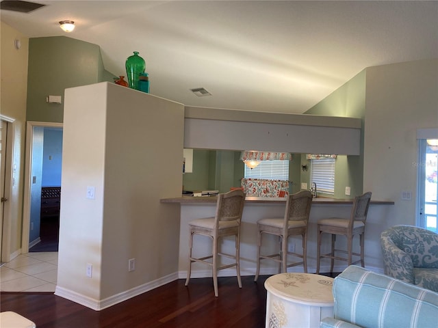 kitchen with a breakfast bar, lofted ceiling, and tile floors