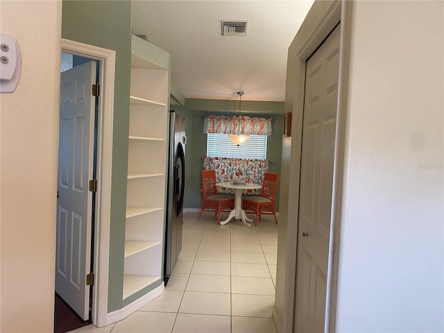 corridor featuring a textured ceiling and light tile flooring