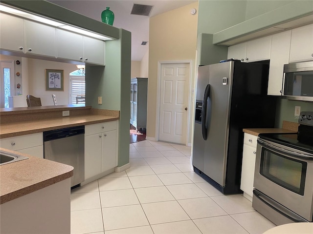 kitchen featuring light tile floors, appliances with stainless steel finishes, and white cabinetry