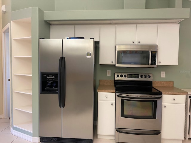 kitchen with light tile flooring, stainless steel appliances, and white cabinetry