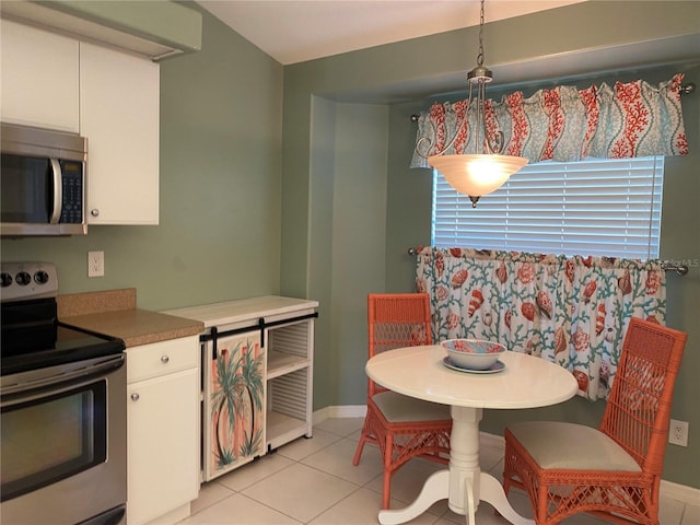 kitchen with light tile floors, white cabinets, hanging light fixtures, and stainless steel appliances