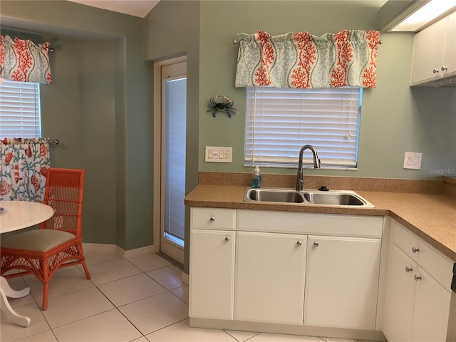 kitchen featuring light tile floors, white cabinetry, and sink