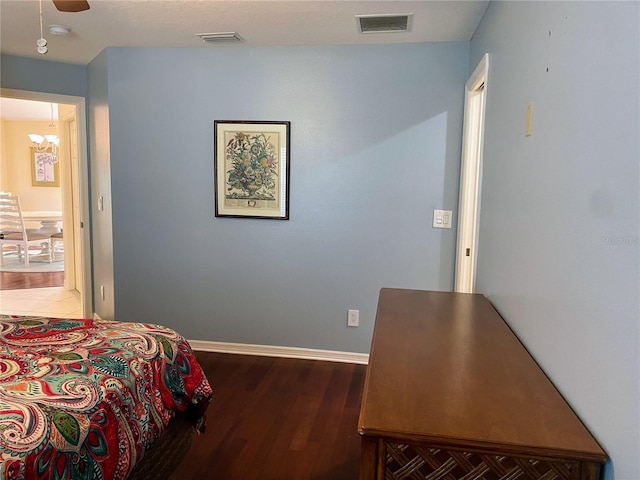 bedroom featuring dark hardwood / wood-style floors and ceiling fan with notable chandelier