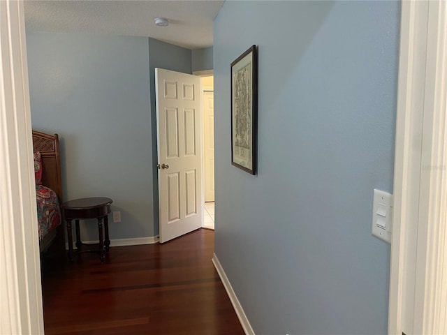 hall with a textured ceiling and dark wood-type flooring