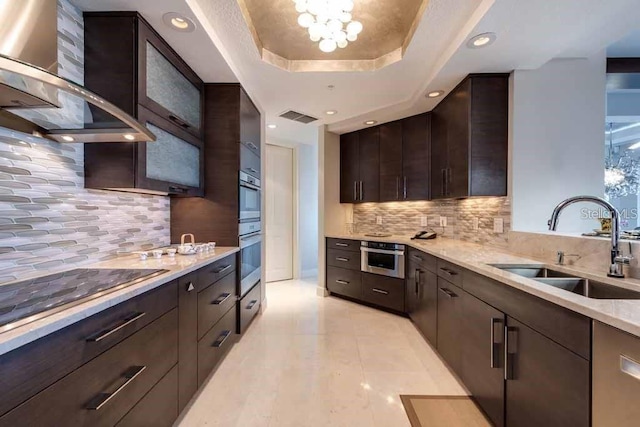 kitchen featuring sink, light tile floors, tasteful backsplash, a raised ceiling, and wall chimney exhaust hood