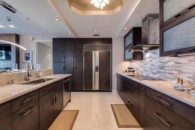 kitchen featuring light stone countertops, backsplash, sink, paneled refrigerator, and black electric stovetop