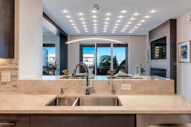 kitchen with a fireplace, sink, and light stone countertops