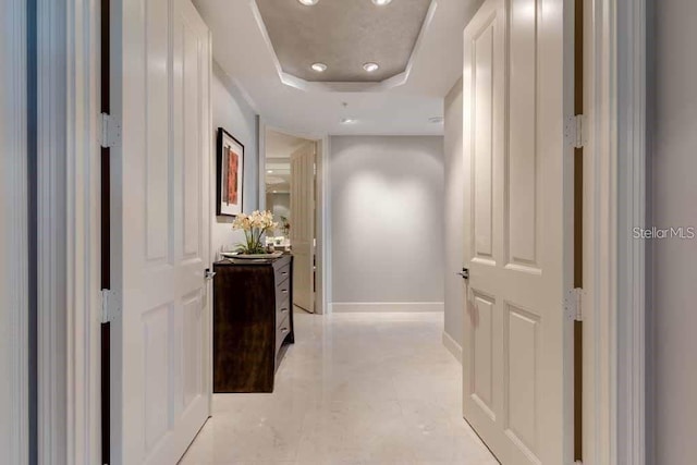 corridor featuring a raised ceiling and light tile floors