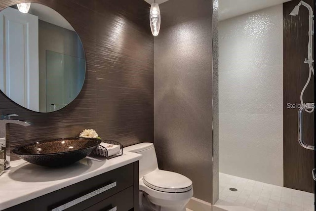 bathroom featuring toilet, a shower, tile flooring, tasteful backsplash, and vanity