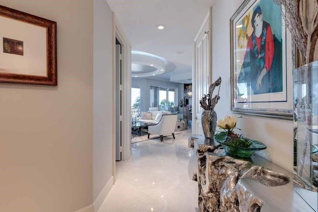 hallway featuring a tray ceiling and light tile floors