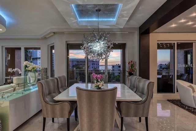 dining area featuring a tray ceiling, light tile floors, and an inviting chandelier