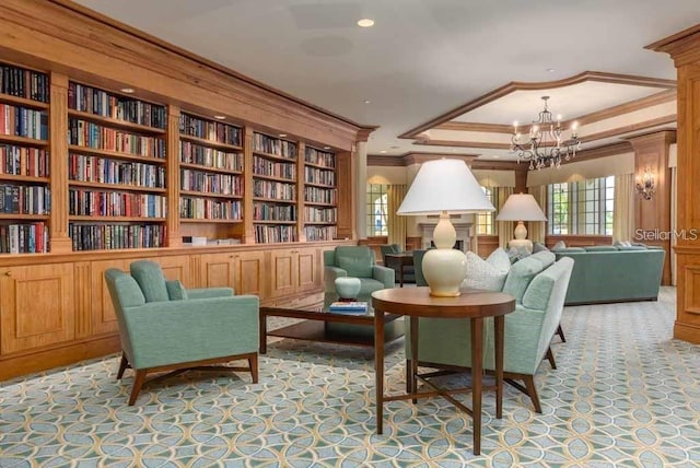 living area featuring a notable chandelier, a raised ceiling, built in shelves, and ornamental molding