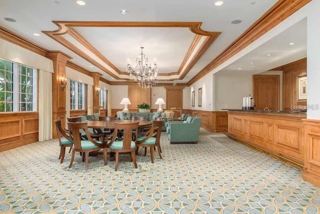 carpeted dining area with a notable chandelier, a tray ceiling, and ornamental molding