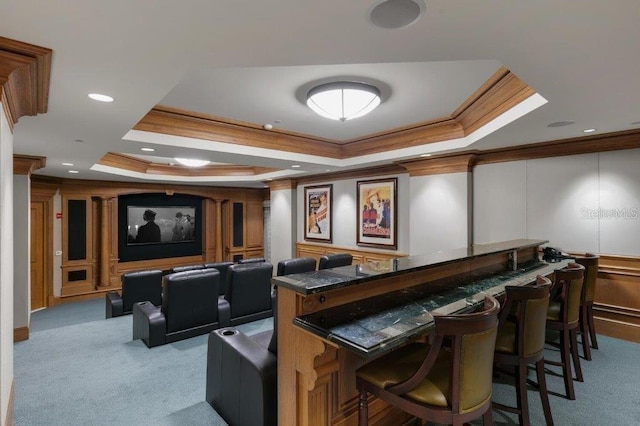 carpeted home theater room with a tray ceiling and crown molding