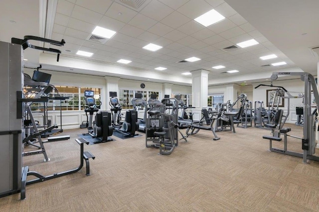 exercise room with light carpet, decorative columns, and a drop ceiling