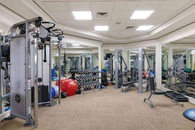 gym featuring light carpet, ornamental molding, and a paneled ceiling