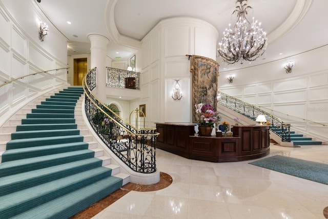 interior space with a chandelier, a decorative wall, a high ceiling, and ornamental molding