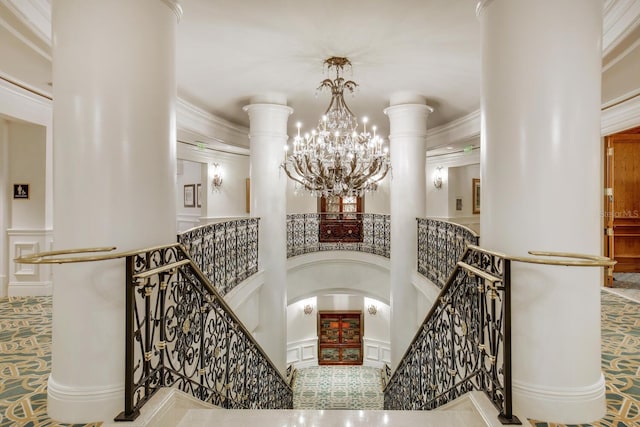 staircase with a notable chandelier, crown molding, and a towering ceiling