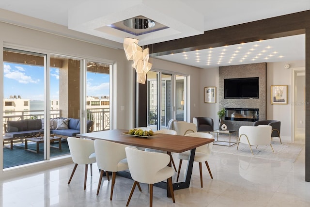 dining area featuring beamed ceiling, a large fireplace, and baseboards