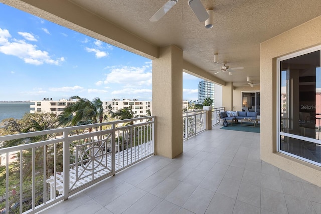 balcony featuring outdoor lounge area, a ceiling fan, and a water view