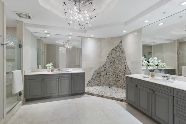 full bathroom with visible vents, a sink, a tray ceiling, an inviting chandelier, and a shower stall