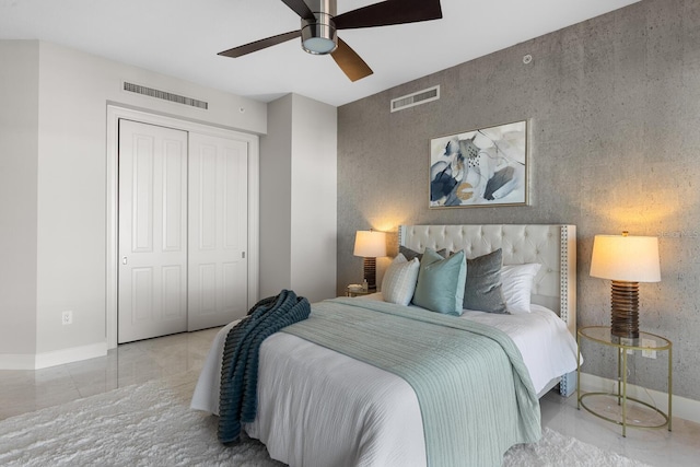 bedroom featuring visible vents, a closet, ceiling fan, and an accent wall