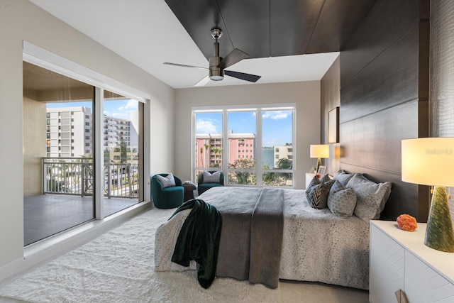 carpeted bedroom featuring a city view, access to exterior, multiple windows, and a ceiling fan