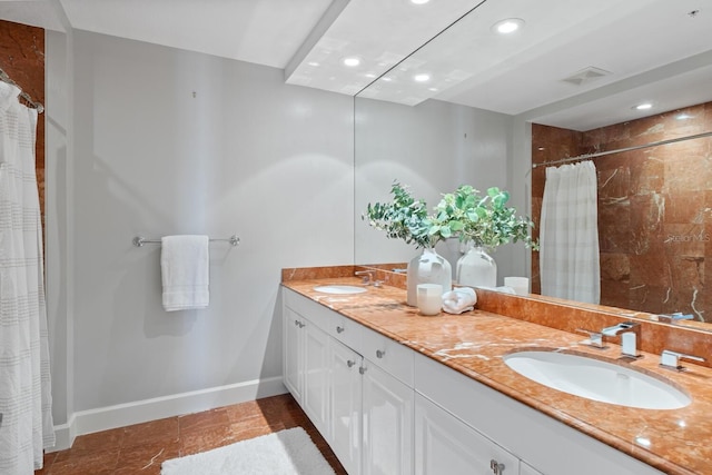 bathroom featuring a sink, visible vents, baseboards, and double vanity