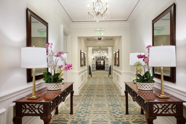 hallway with a decorative wall, a notable chandelier, crown molding, and a wainscoted wall