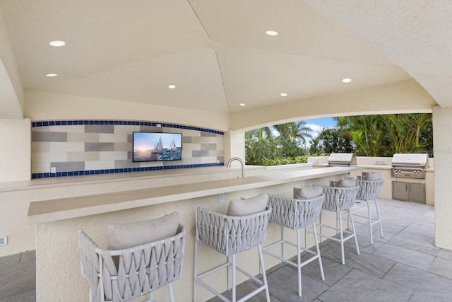 view of patio featuring outdoor wet bar, exterior kitchen, and grilling area