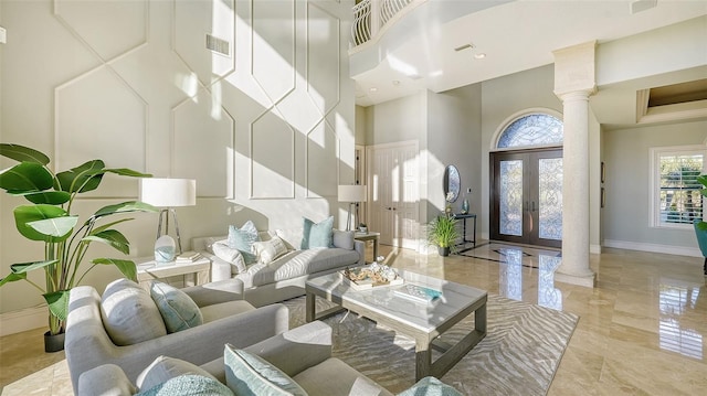 living room featuring a towering ceiling and decorative columns