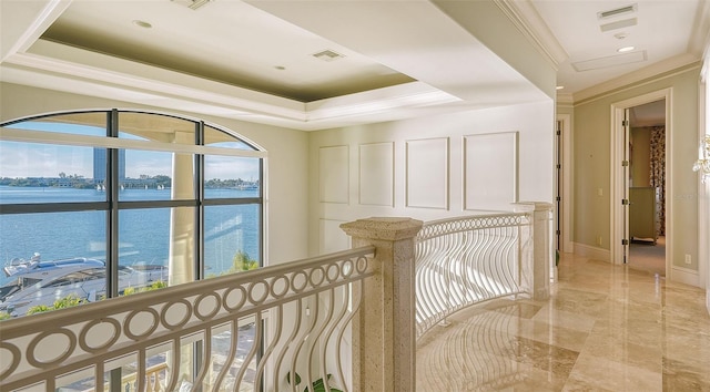 hall featuring a raised ceiling, ornamental molding, and a water view