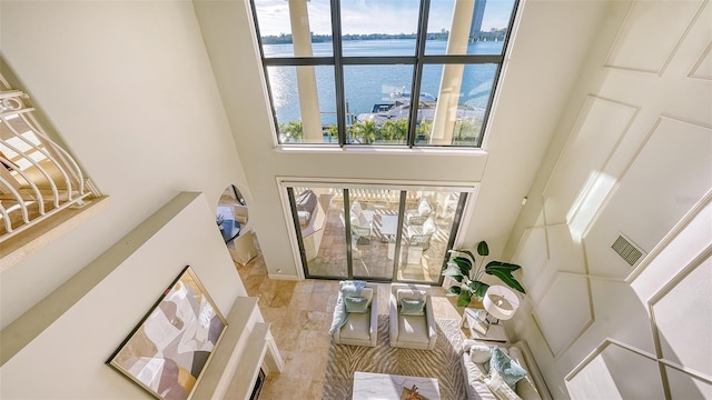 living room featuring a towering ceiling and a water view