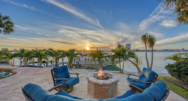 patio terrace at dusk with a water view and an outdoor fire pit