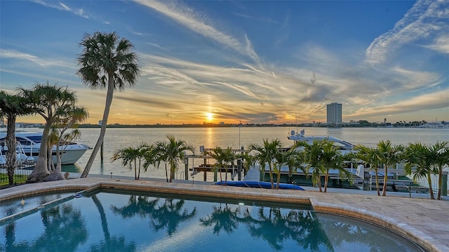 pool at dusk featuring a water view