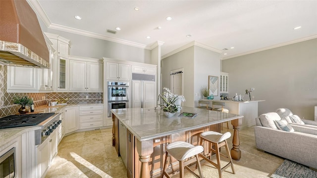 kitchen with white cabinetry, appliances with stainless steel finishes, wall chimney range hood, and a kitchen island