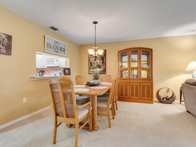 carpeted dining space featuring a chandelier