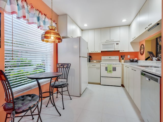 kitchen with light tile flooring, light stone countertops, white appliances, white cabinetry, and sink