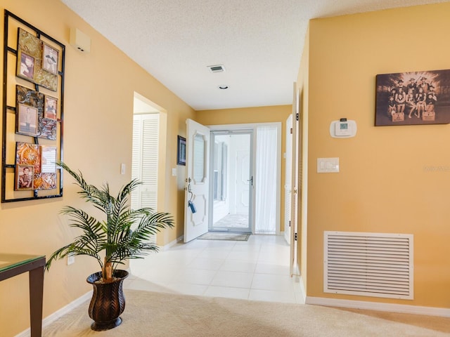 carpeted foyer entrance with a textured ceiling