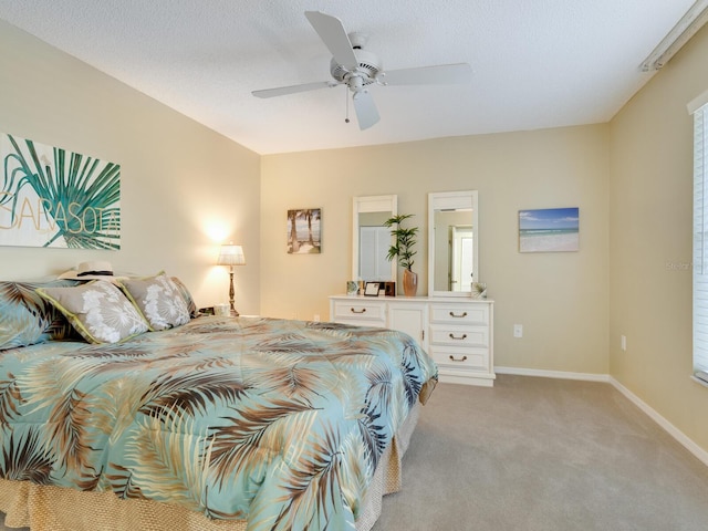 bedroom featuring light colored carpet, ceiling fan, and a textured ceiling