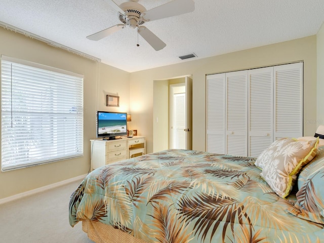 bedroom with a closet, carpet flooring, ceiling fan, and a textured ceiling