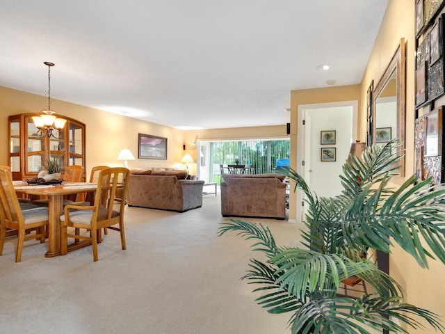 carpeted dining area with a chandelier