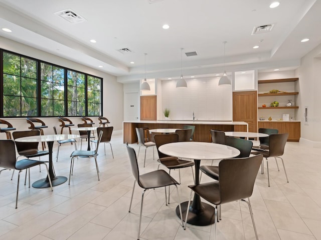 dining area with a raised ceiling and light tile floors