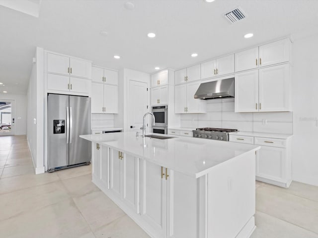 kitchen with extractor fan, sink, stainless steel appliances, an island with sink, and white cabinetry