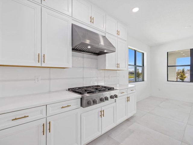 kitchen featuring exhaust hood, white cabinets, stainless steel gas stovetop, light tile patterned floors, and backsplash