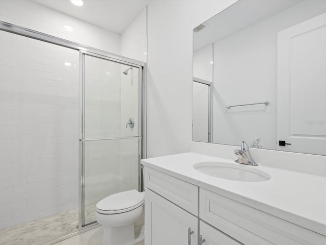 bathroom with vanity, a shower with shower door, and toilet