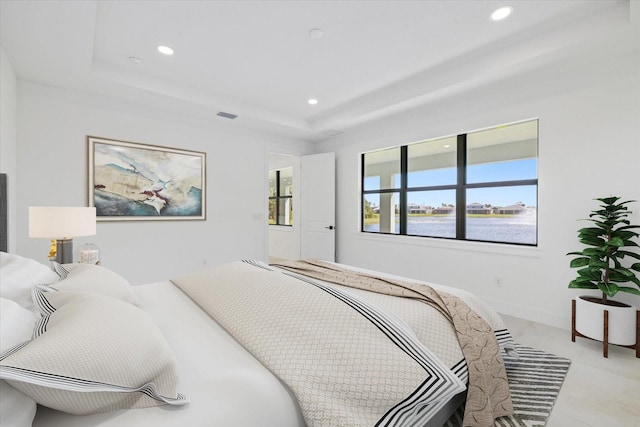 bedroom with a water view and a raised ceiling