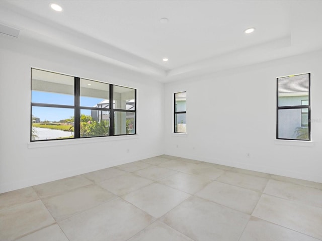 tiled spare room with a tray ceiling