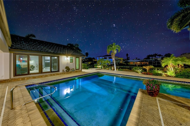 pool at night with a patio area